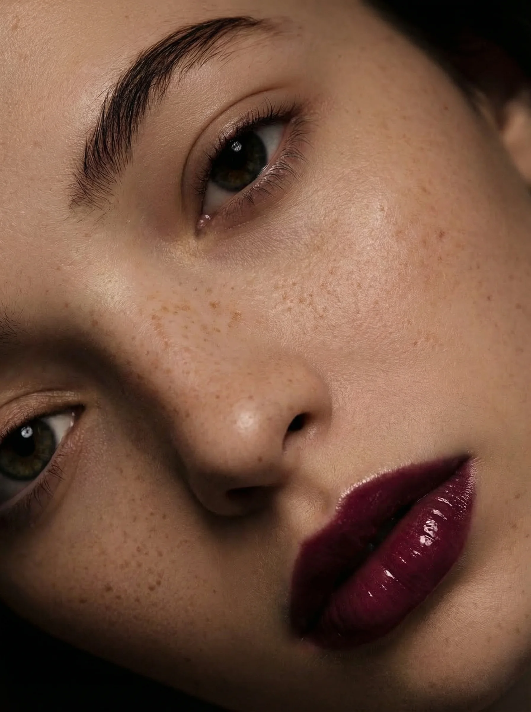 AI-generated beauty portrait: freckled skin and glossy plum lips, seen from above