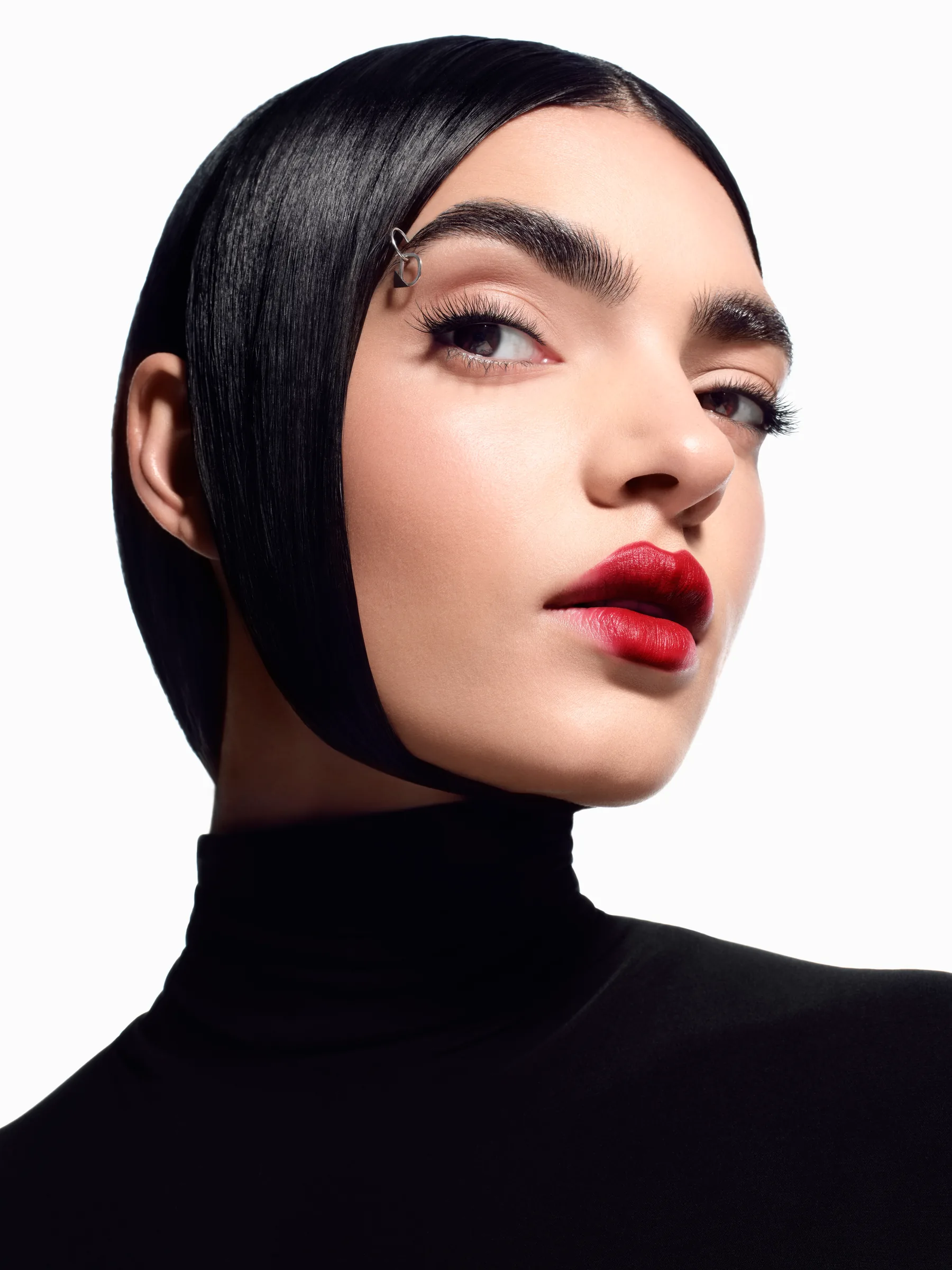 Model with slicked black hair, red lips and a D monogram eyebrow piercing — Ciglione Mascara campaign