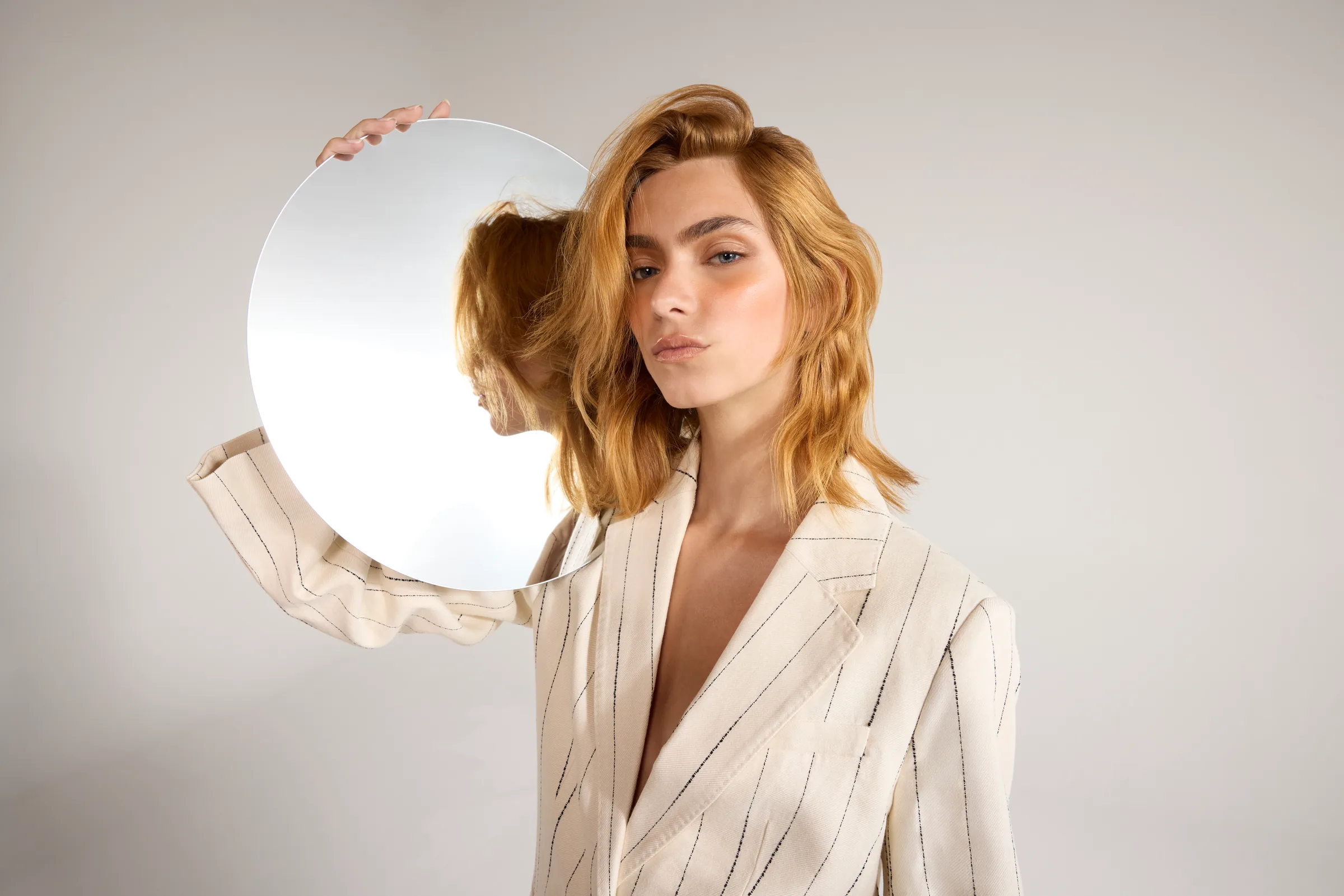 Model holding a round mirror, campaign photo