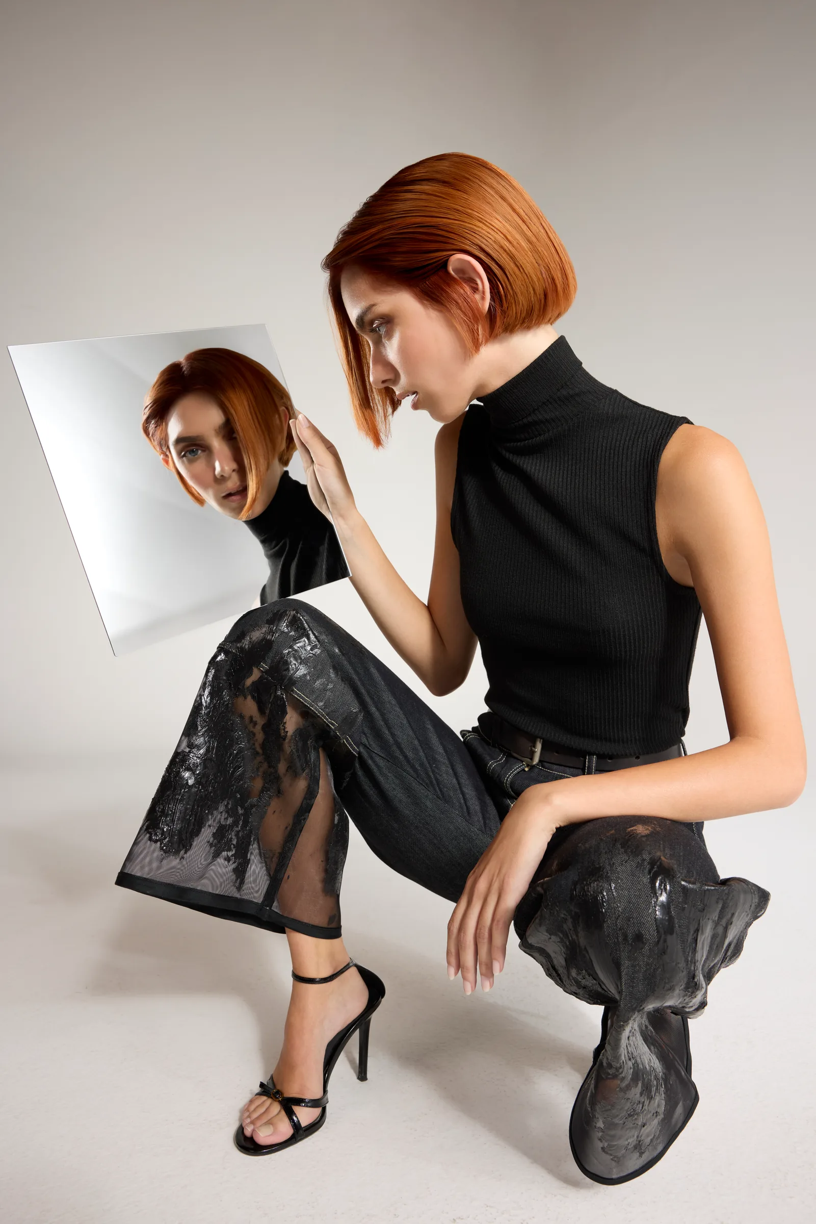 Model with a copper bob crouching beside a mirror
